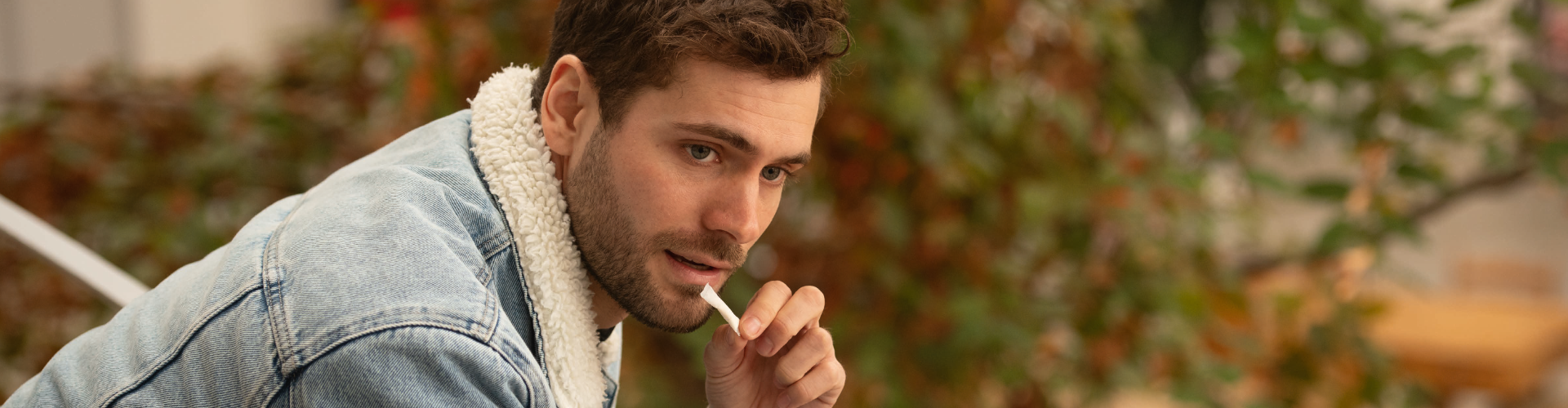 Ein Mann nimmt ein Nikotinbeutelchen, während er auf einer Bank sitzt